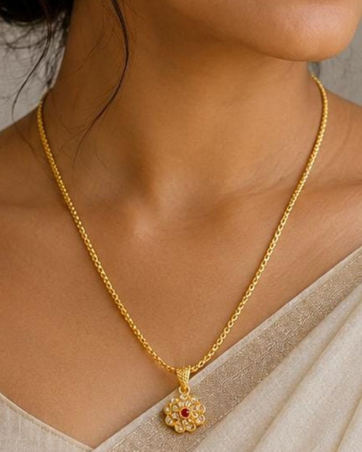 Beautiful gold plated necklace featuring a delicate chain and floral-inspired pendant adorned with sparkling stones and a pink center stone. Perfect for traditional wear, festive occasions, weddings, daily wear, and gifting.