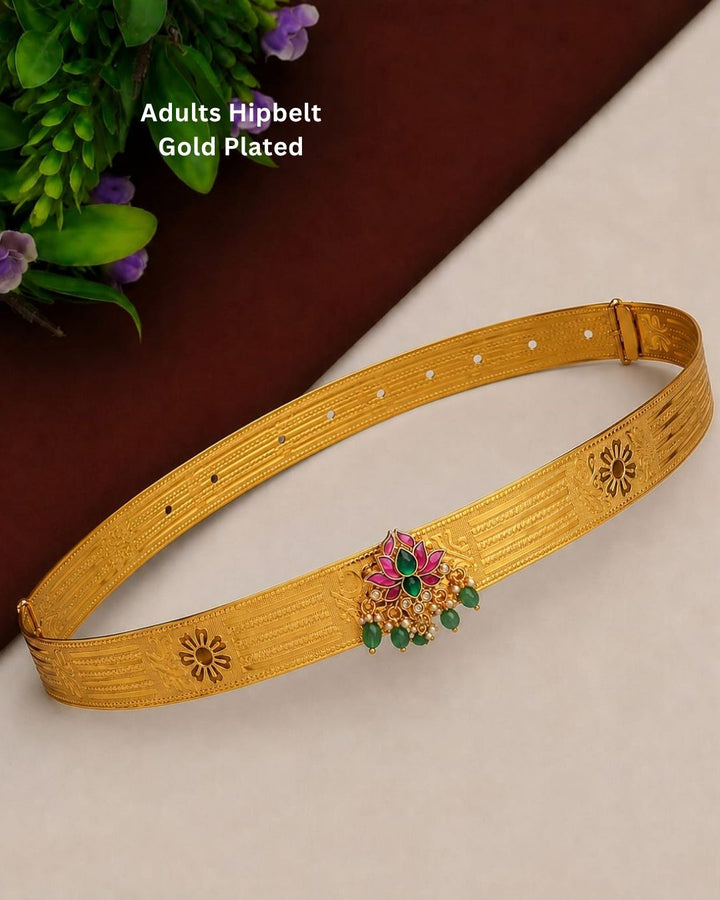 Beautiful gold plated adult hip belt featuring a wide intricately engraved band with traditional floral motifs and a decorative centerpiece adorned with green and pink stones, clear stones, and elegant green bead drops. Perfect for traditional wear, weddings, festive occasions, bridal styling, parties, and gifting.