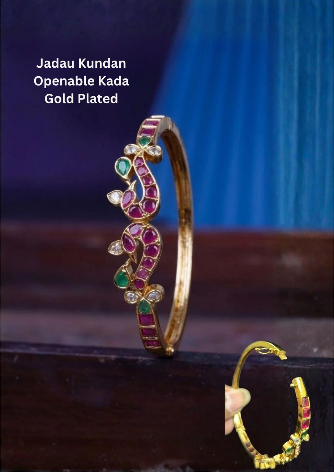 A slender 18k gold plated openable kada bangle showcasing a stylized abstract twin peacock motif along the top framework. The artistic design is inlaid with smooth cabochon ruby pink and teardrop emerald green gemstones, highlighted by clear white zircon diamond crystals at the tips and tails.