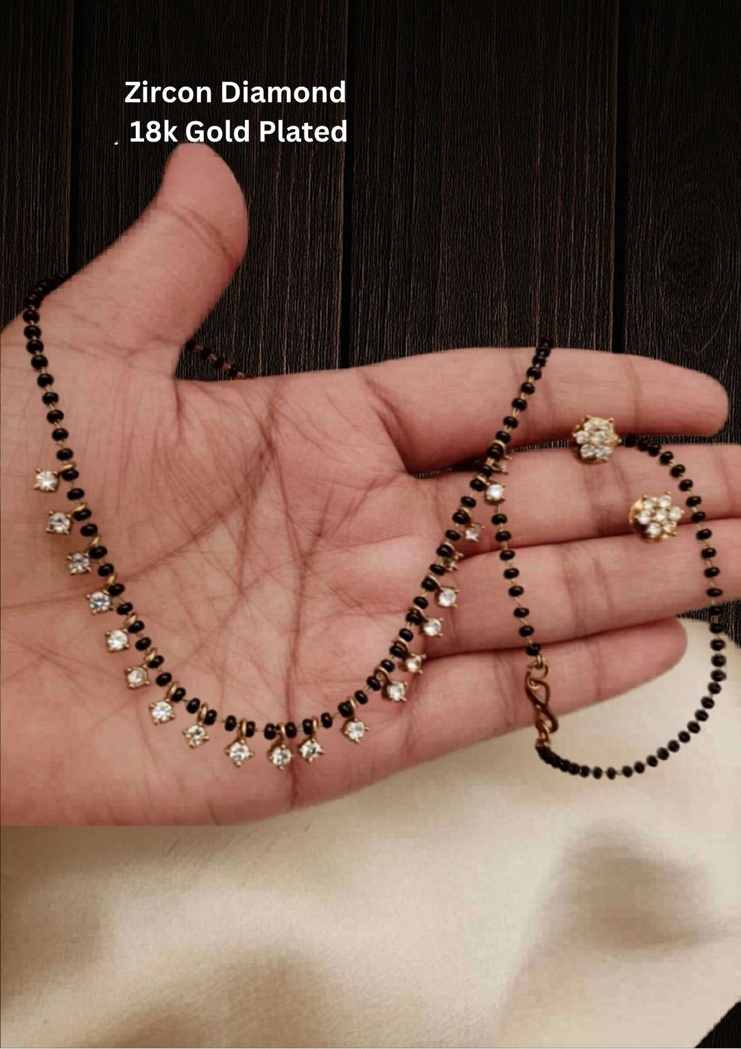 This is a simple and delicate Zircon Diamond Mangalsutra Set with matching earrings. It features a modern, lightweight look designed for everyday wear. The style blends the traditional protective black beads with trendy hanging charms.