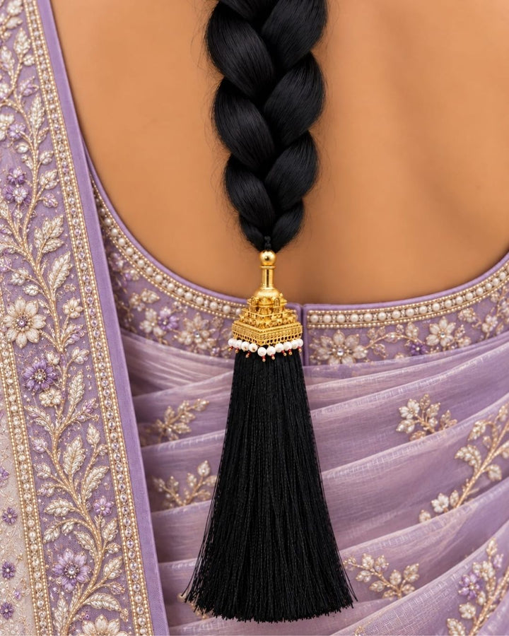 Elegant gold plated Jada Gantalu featuring a detailed temple-style design, white pearl accents, red bead detailing, and long flowing black tassels, perfect for traditional occasions and bridal looks.
