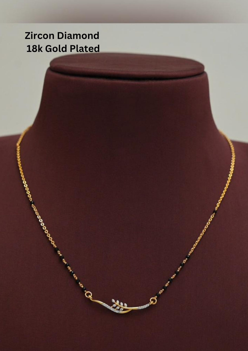 Modern Zircon Diamond gold plated mangalsutra necklace The design features a delicate gold link chain transitioning into sections of traditional small black beads on both sides. The central pendant showcases a sleek, contemporary curved V-shape and a stylized butterfly or floral motif encrusted with sparkling white cubic zirconia stones. This elegant neckpiece perfect for daily wear, office wear, and casual outfits.