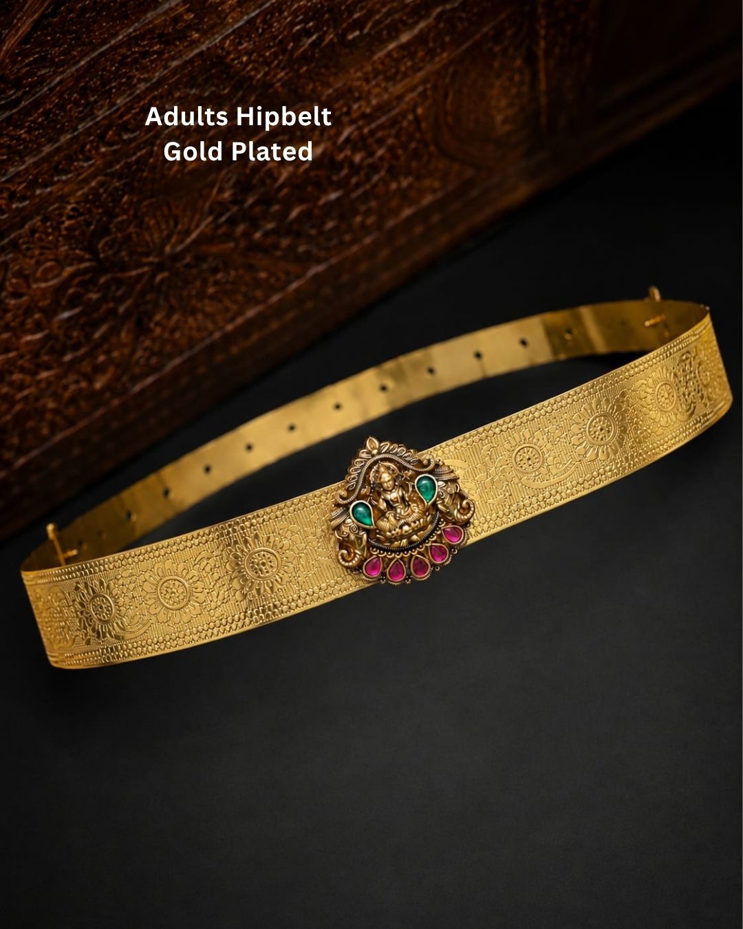 Beautiful gold plated adult hip belt featuring an intricately engraved wide band with a traditional Lakshmi centerpiece decorated with ruby and green stones. Perfect for traditional wear, weddings, festive occasions, bridal styling, parties, and gifting.