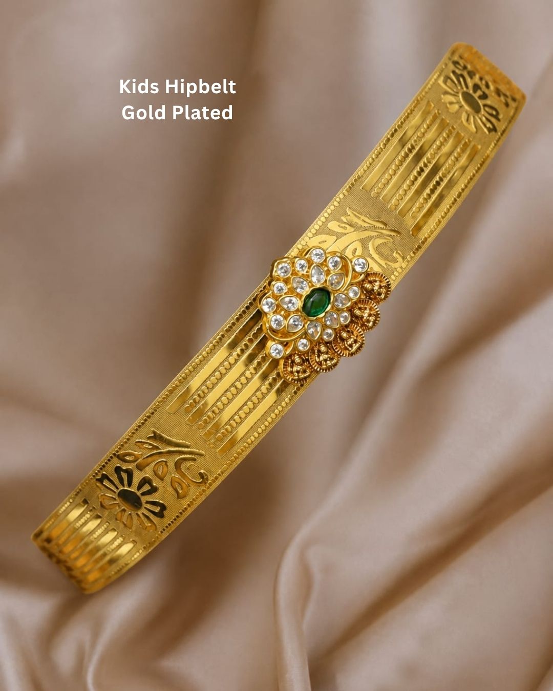 Beautiful gold plated kids hip belt featuring an intricately engraved wide band with floral motifs and a central green gemstone surrounded by sparkling clear stones. Perfect for traditional wear, weddings, festive occasions, cultural celebrations, and gifting.