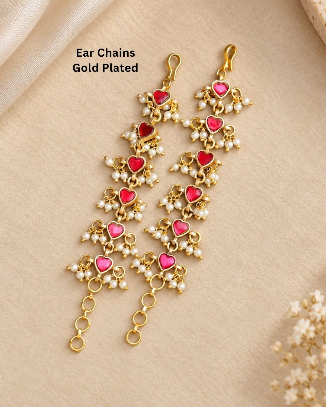 Pair of gold plated designer ear chains with repeating pink heart motifs, white pearl embellishments, and circular adjustment links.