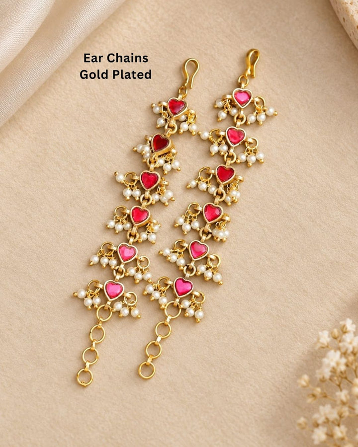 Pair of gold plated designer ear chains with repeating pink heart motifs, white pearl embellishments, and circular adjustment links.