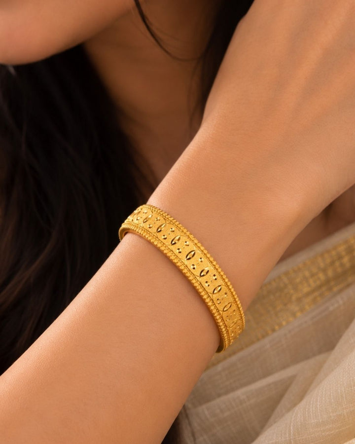 Traditional gold plated designer bangles featuring detailed repeating embossed motifs, textured borders, and a polished gold finish, perfect for festive, wedding, and traditional occasions.