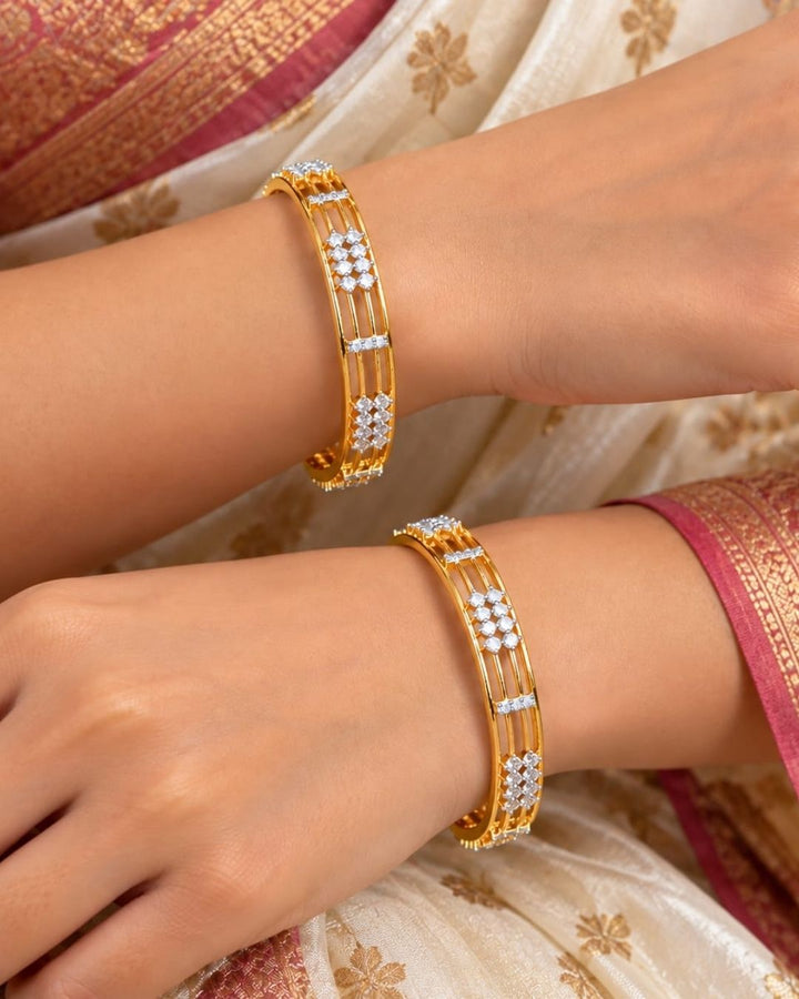 Gold plated designer bangles featuring a sleek triple-line structure with sparkling white CZ floral stone clusters and rectangular stone accents.