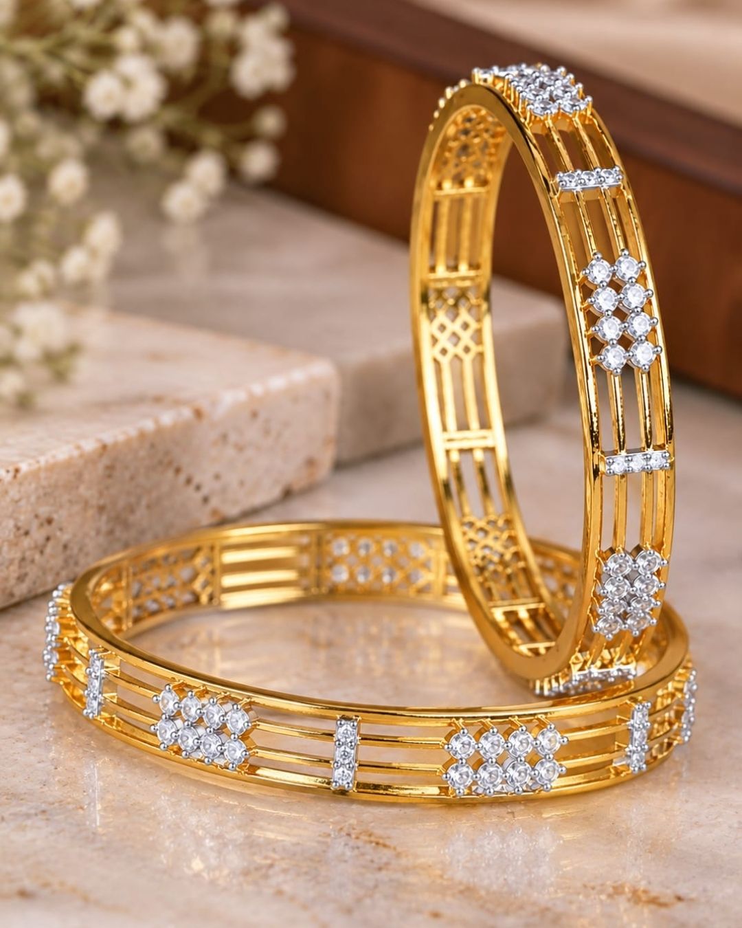 Gold plated designer bangles featuring a sleek triple-line structure with sparkling white CZ floral stone clusters and rectangular stone accents.