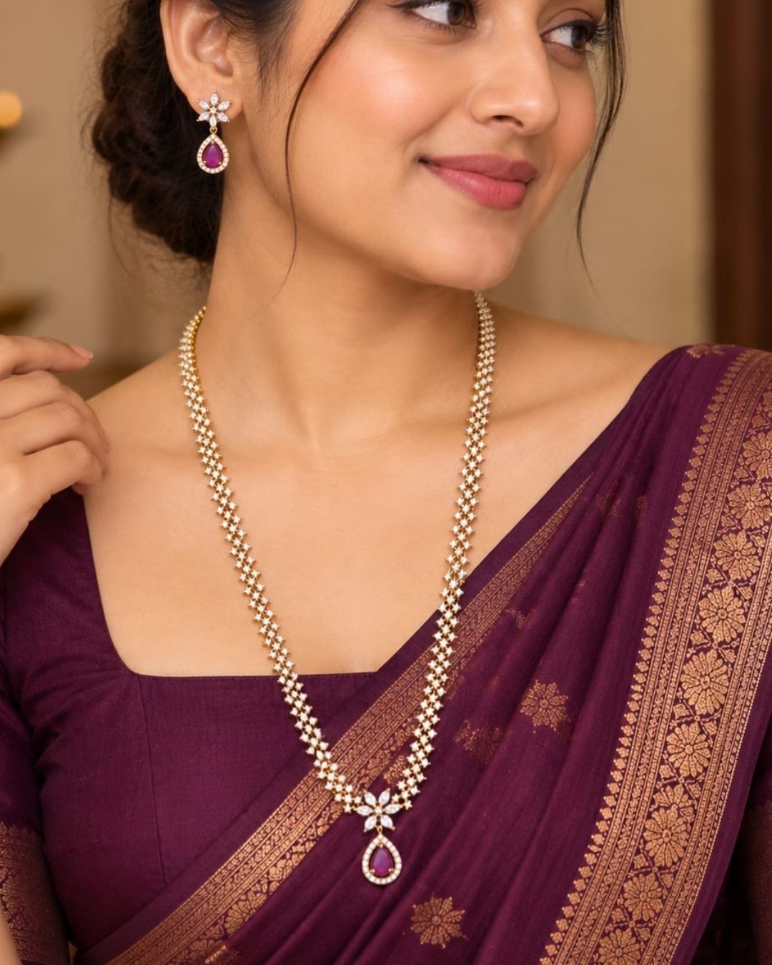 Gold plated zircon necklace and matching earrings displayed on a black jewellery bust against a rich burgundy background.