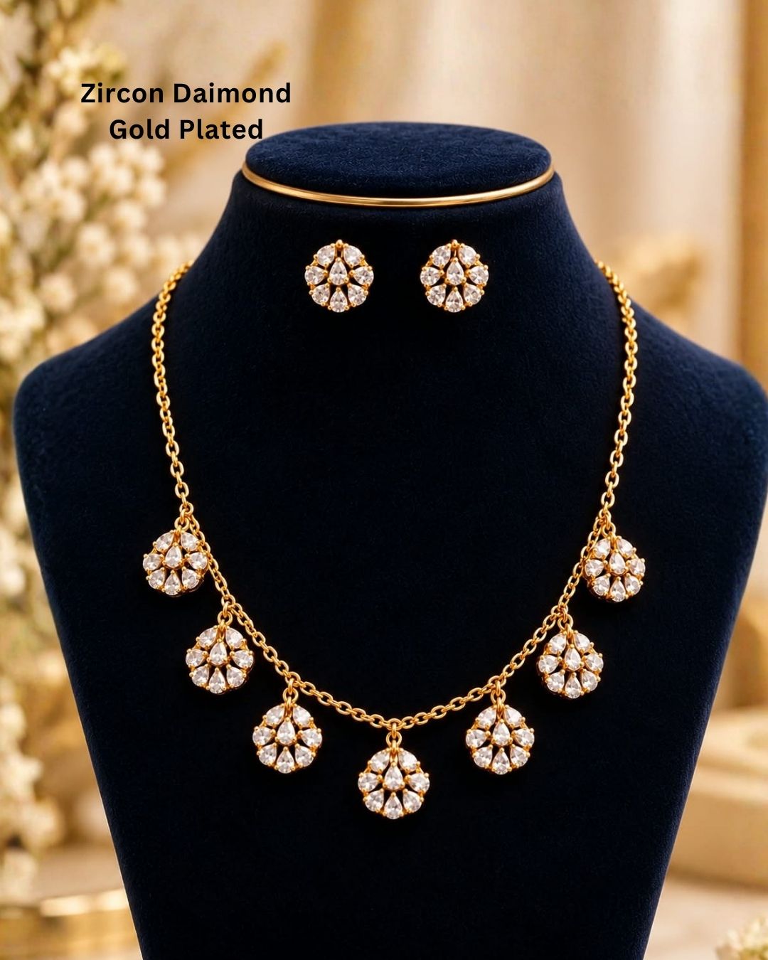 Elegant gold plated necklace with sparkling white zircon stones and floral dangling motifs displayed on a navy blue jewellery bust.