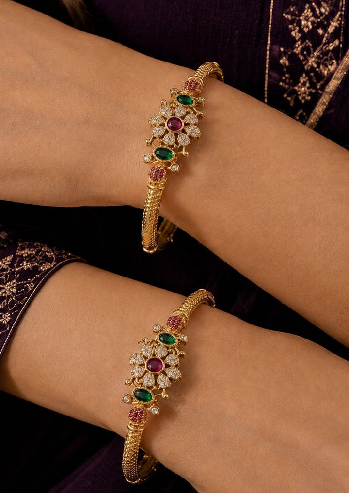 Close up of South Indian woman Hands wearing Jadau Kundan Gold Plated Flower Bangles with beautiful flower-shaped design with red , green and white stones detailing, colorful kundan work, and rich traditional jewelry style that gives an elegant festive and bridal look. The bangles have lightweight comfort, skin-friendly finish, sweat proof quality, anti-fade colour, and are perfect for weddings, pooja functions, receptions, festivals, family functions, and party wear.