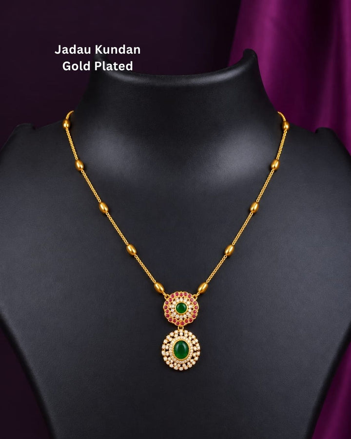 Traditional gold plated designer necklace featuring a delicate beaded chain and an elegant double green stone pendant with ruby-colored and white stone accents.