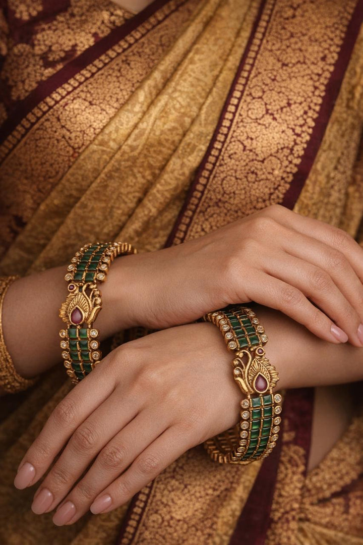 Close-up of hands wearing gold bangles with green kempu peacock 