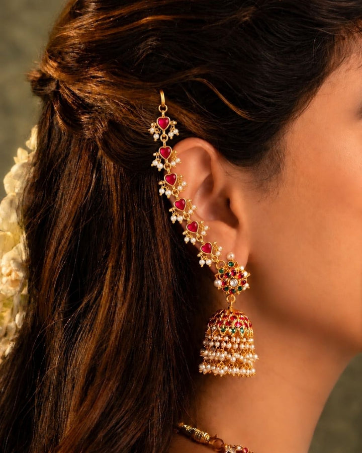 Pair of gold plated designer ear chains with repeating pink heart motifs, white pearl embellishments, and circular adjustment links.