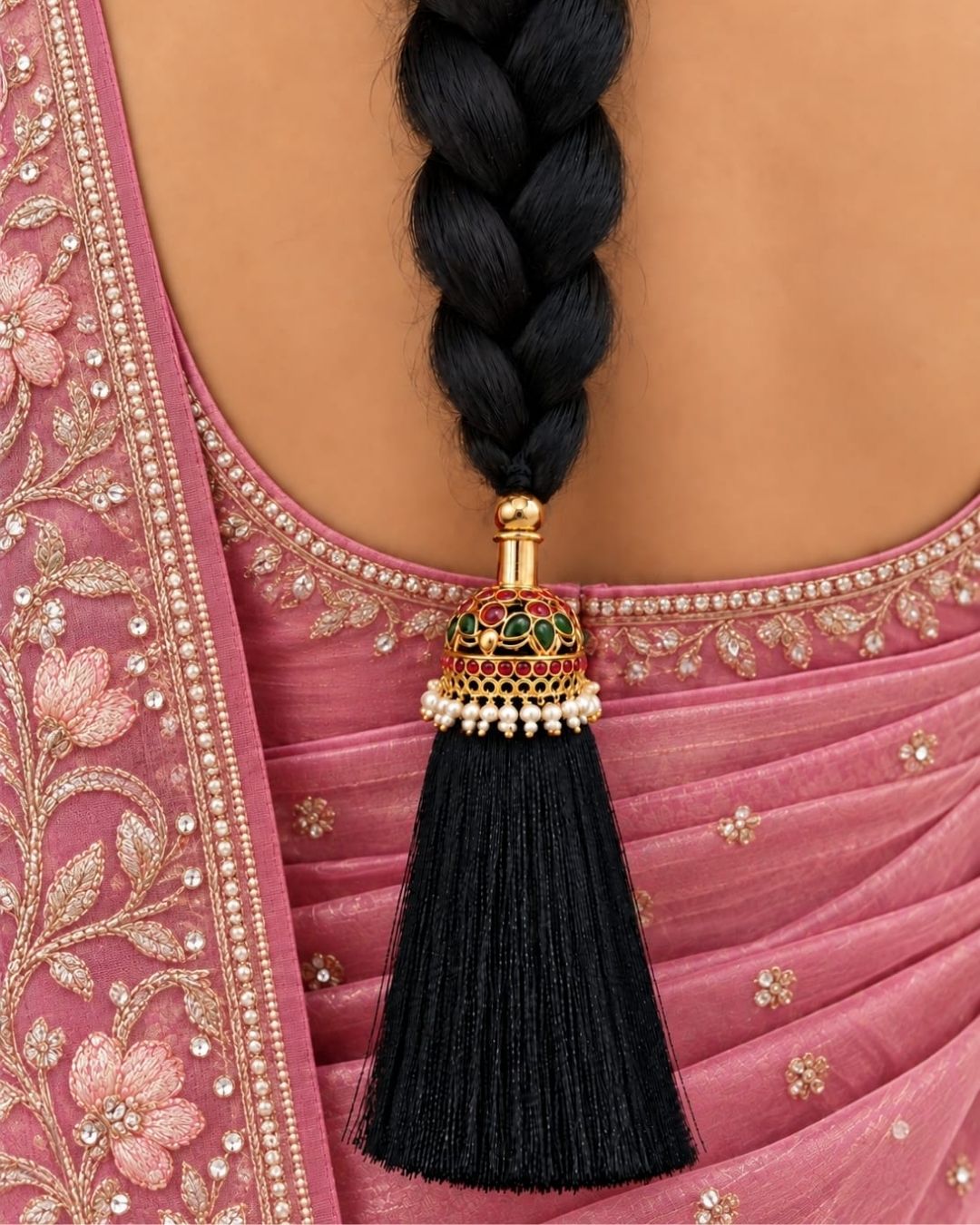 Elegant gold plated Jada Gantalu with intricate dome-shaped detailing, green and ruby stones, pearl accents, and long black thread tassels, perfect for bridal and festive hairstyles.