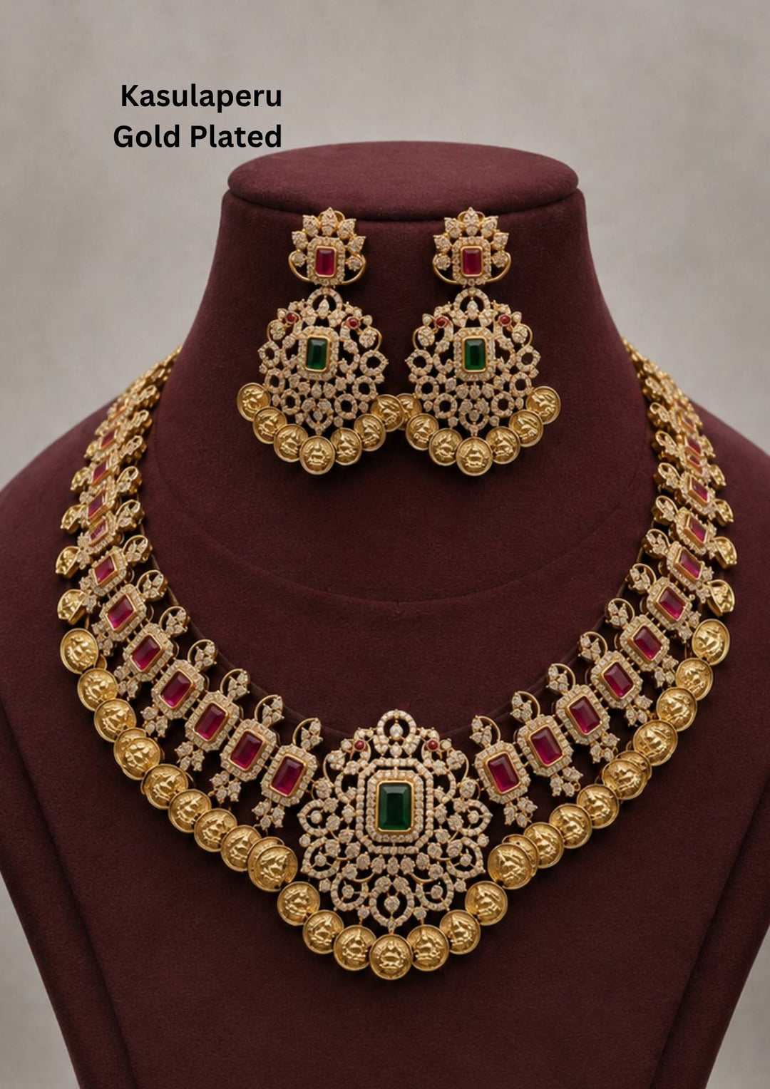 Traditional Laxmi kasulaperu gold plated long haram necklace featuring detailed coin style motifs throughout the chain with an intricately designed center pendant studded with white stones and green stone accents. The matching earrings have elegant filigree detailing with hanging gold beads, creating a rich South Indian temple jewelry appearance suitable for weddings, poojas and bridal occasions.