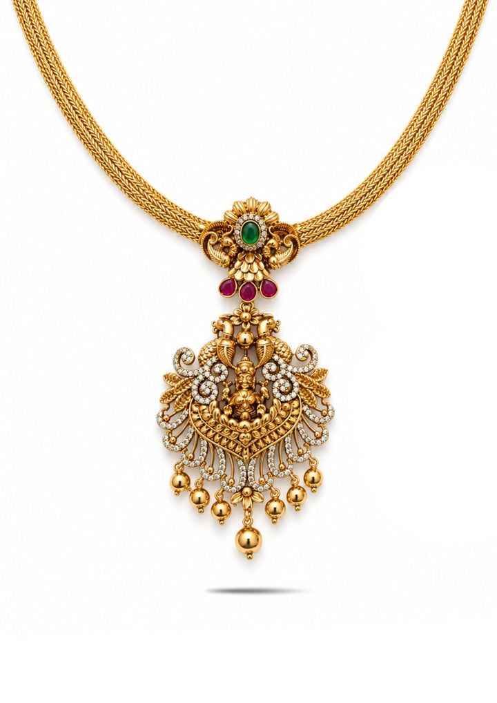 Laxmi Devi Gold Plated temple necklace chain designed with smooth layered chain pattern and traditional pendant with Goddess Laxmi carving, floral motifs, green center stone detailing, sparkling white zircon stones, and simple gold beadsam hangings. The necklace is finished in rich antique gold plating that gives a royal South Indian ethnic jewelry look. This lightweight necklace comes with sweat proof quality, anti-fade colour, skin-friendly finish, smooth fitting, and is suitable for weddings, 