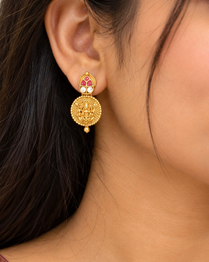 Traditional gold plated designer necklace and earrings set featuring multiple Goddess Lakshmi coin motifs, intricate temple-inspired detailing, ruby-colored stone accents, and matching decorative earrings, perfect for festive, wedding, and traditional occasions.