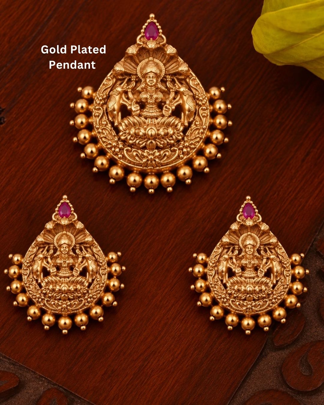 Elegant gold plated Lakshmi Devi jewellery set featuring intricately detailed goddess motifs, red teardrop stones, decorative gold beads, and matching statement earrings, perfect for bridal, festive, and traditional occasions.