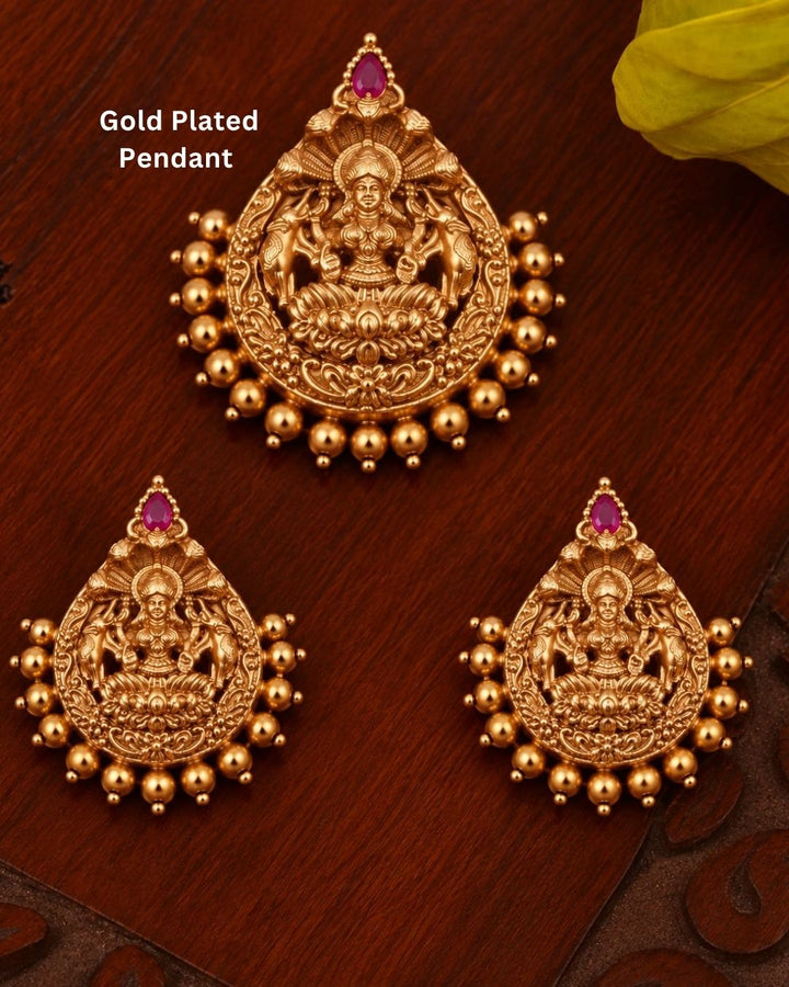 Elegant gold plated Lakshmi Devi jewellery set featuring intricately detailed goddess motifs, red teardrop stones, decorative gold beads, and matching statement earrings, perfect for bridal, festive, and traditional occasions.