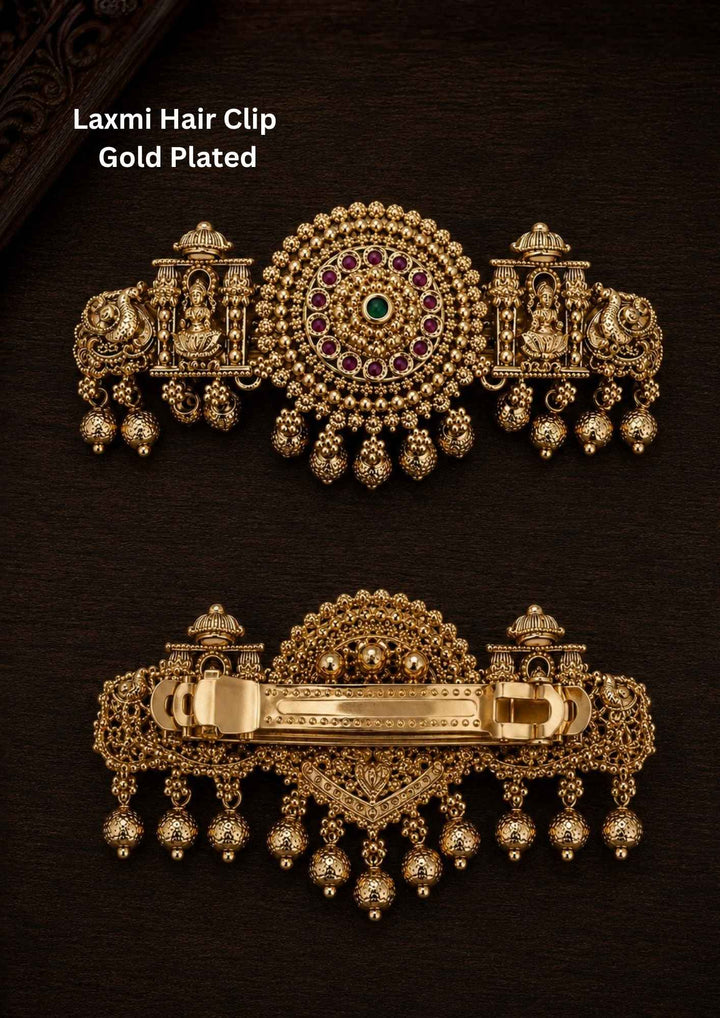 Gold plated Laxmi hair clip with antique finish, designed with Lord Lakshmi in sitting in a temple, peacocks, circle designed by ruby pink and green stone with hanging gold bead drops in South Indian temple jewelry pattern perfect for bridal hairstyles, Bharatanatyam, weddings, festivals, poojas, sarees, lehengas, and traditional ethnic hair styling with rich royal appearance.