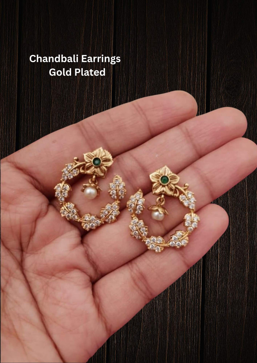 Gold Plated Chandbali Earrings featuring an open-circle hoop decorated with a shimmering white zircon stone leaf pattern. The top stud is shaped like a gold flower with a central green stone and a single white pearl drop hanging in the middle.