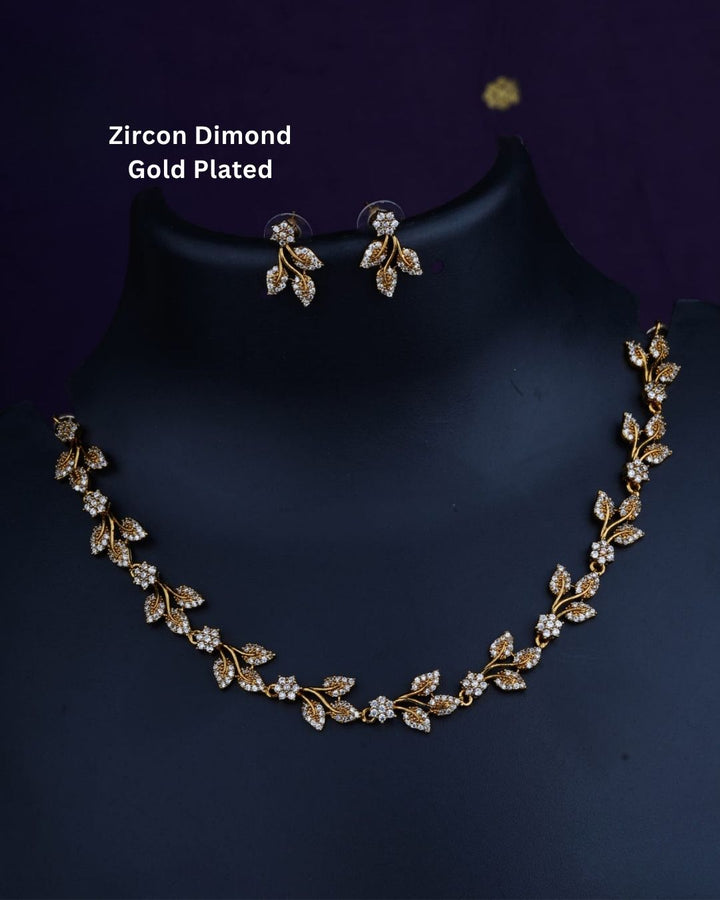 Designer gold plated necklace and earrings set featuring an elegant arrangement of leaf and floral motifs embellished with sparkling white stones, perfect for festive, wedding, and elegant occasions.