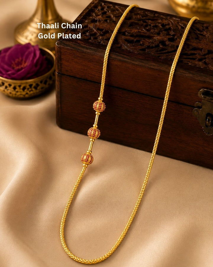Stylish gold plated long chain featuring a fine textured design and three red and gold decorative beads. Perfect for traditional outfits, festive occasions, temple events, and special celebrations.
