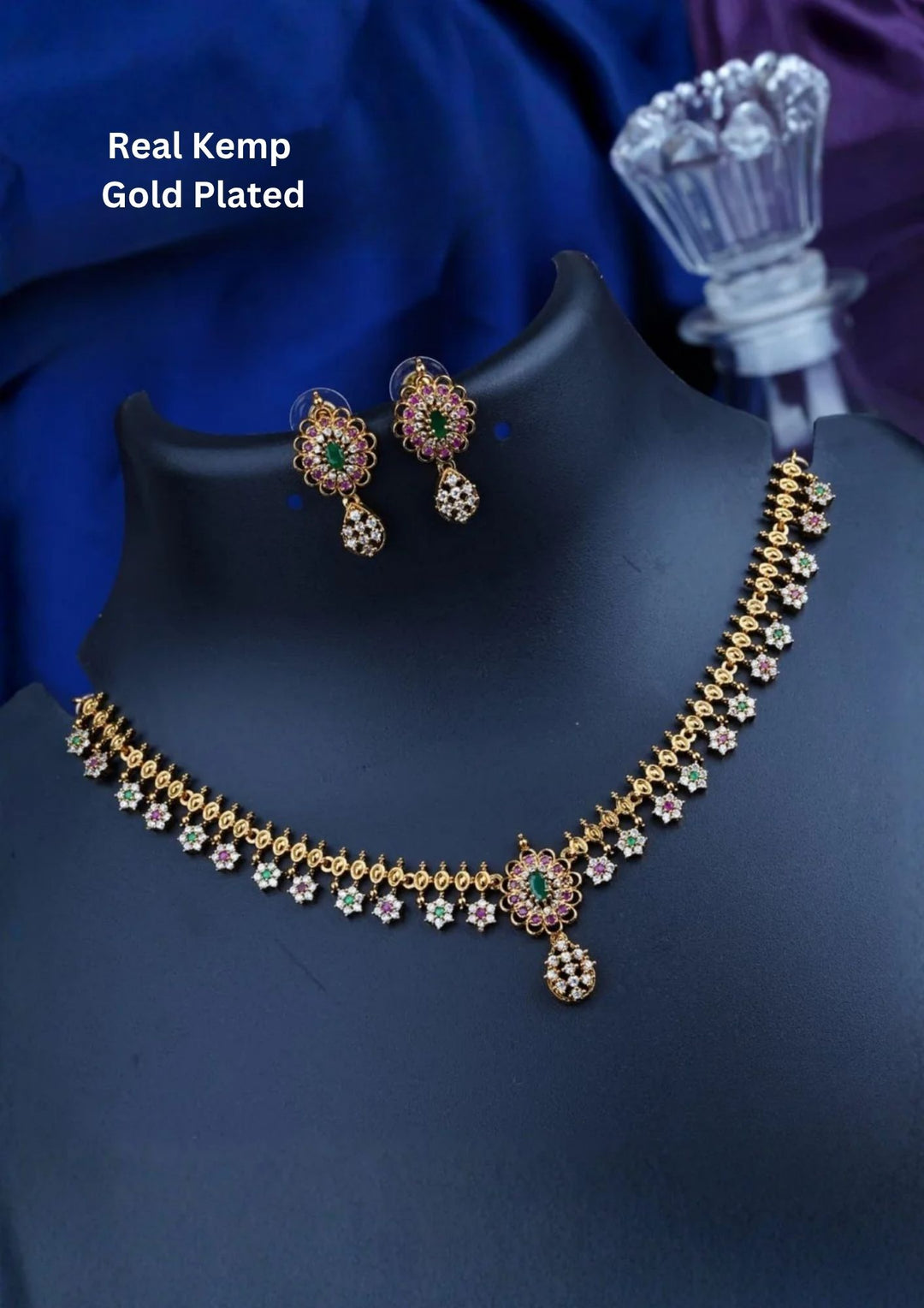 A delicate gold plated choker necklace composed of a continuous row of openwork loop links. The center features a scalloped fringe of small star-shaped flower clusters encrusted with white pure Zirconian diamonds, alternating pink rubies, green emerald cores, and a central matching teardrop cluster pendant.
