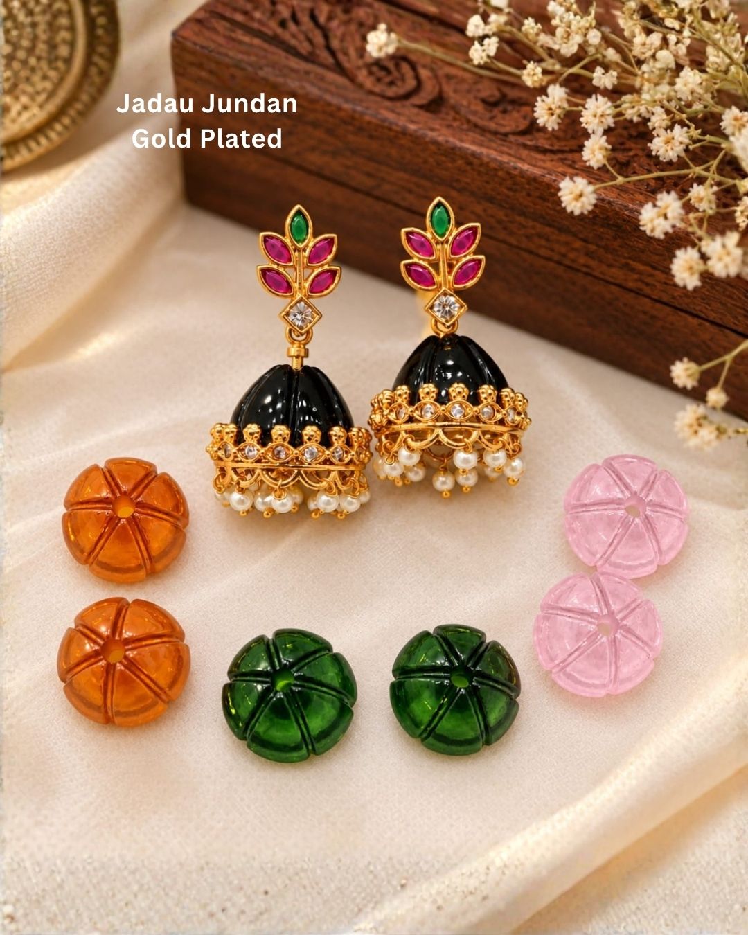 Traditional gold finish jhumka earrings with decorative pink and green leaf motifs, sparkling stones, and pearl hangings with interchangeable color options.