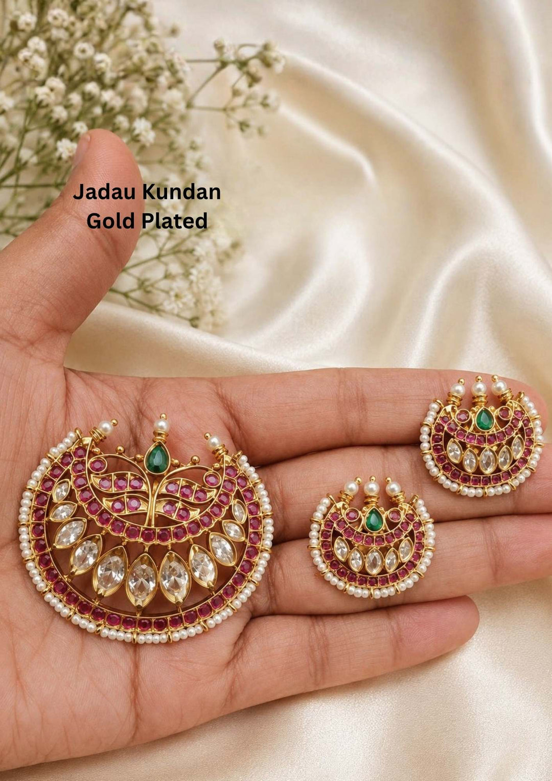 Gold plated Jadau Kundan pendant set featuring a large open hook crescent chandbali pendant and matching smaller stud earrings. The traditional jewelry pieces are decorated with leaf-shaped ruby red stone borders, clear kundan crystal slices arranged in a teardrop pattern, a central tear-shaped green emerald stone accent, and a delicate protective border made of tiny white pearl beads suitable for family gatherings, festivals, parties