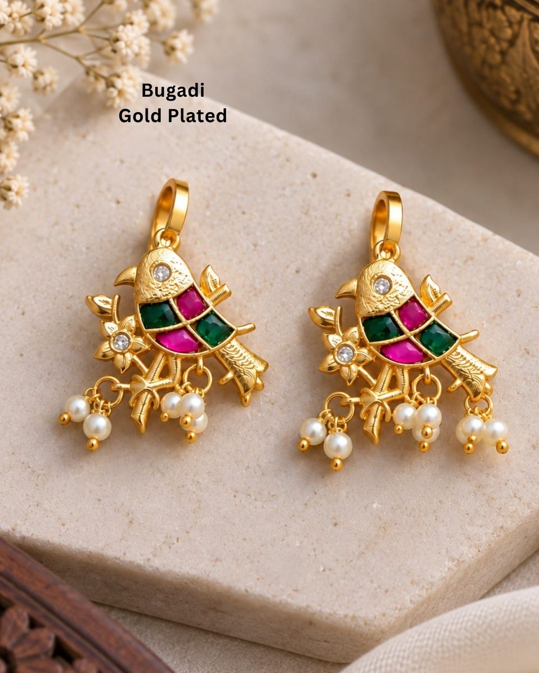 Premium gold plated bugadi earrings featuring an ornate traditional design embellished with green and pink stones, sparkling clear accents, floral detailing, and delicate pearl drops. Perfect for weddings, festive occasions, traditional wear, parties, and gifting.