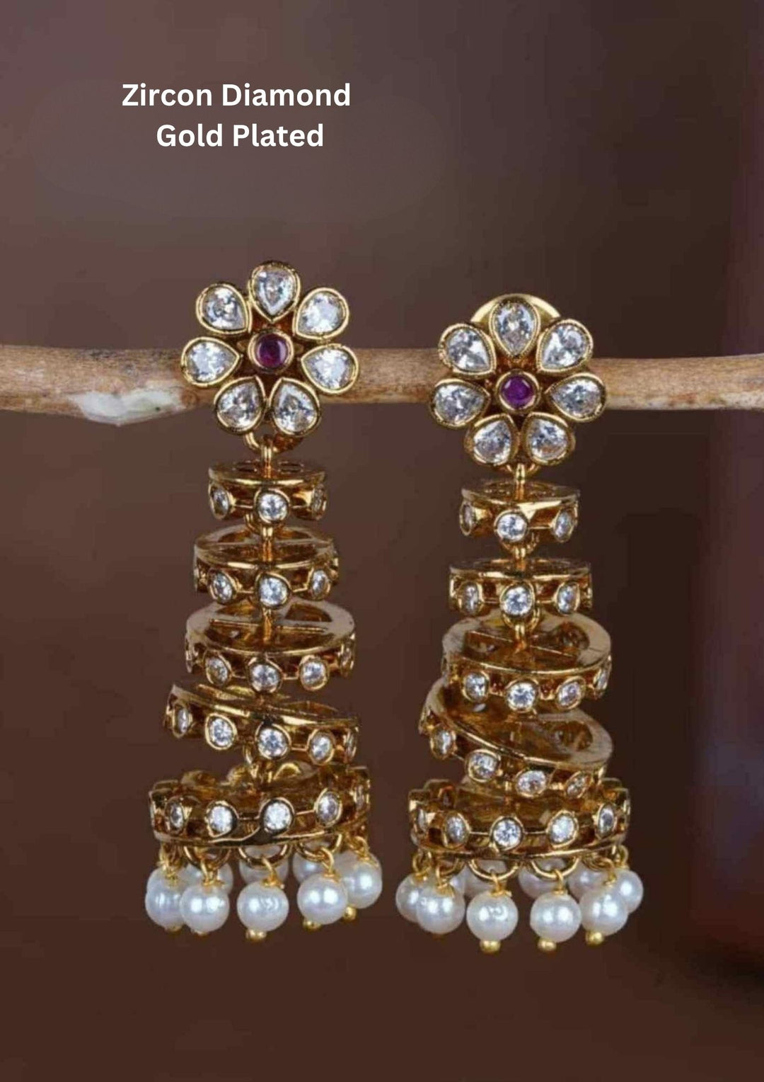 Zircon diamond five layer design gold plated Jhumkas with spiral shaped buttalu design with red, purple and green stone detailing, pearl hanging pattern. The earrings feature shiny gold finish, lightweight comfort, sweat proof quality, anti-fade colour, skin-friendly finish, and are suitable for weddings, festivals, receptions, and pooja functions.