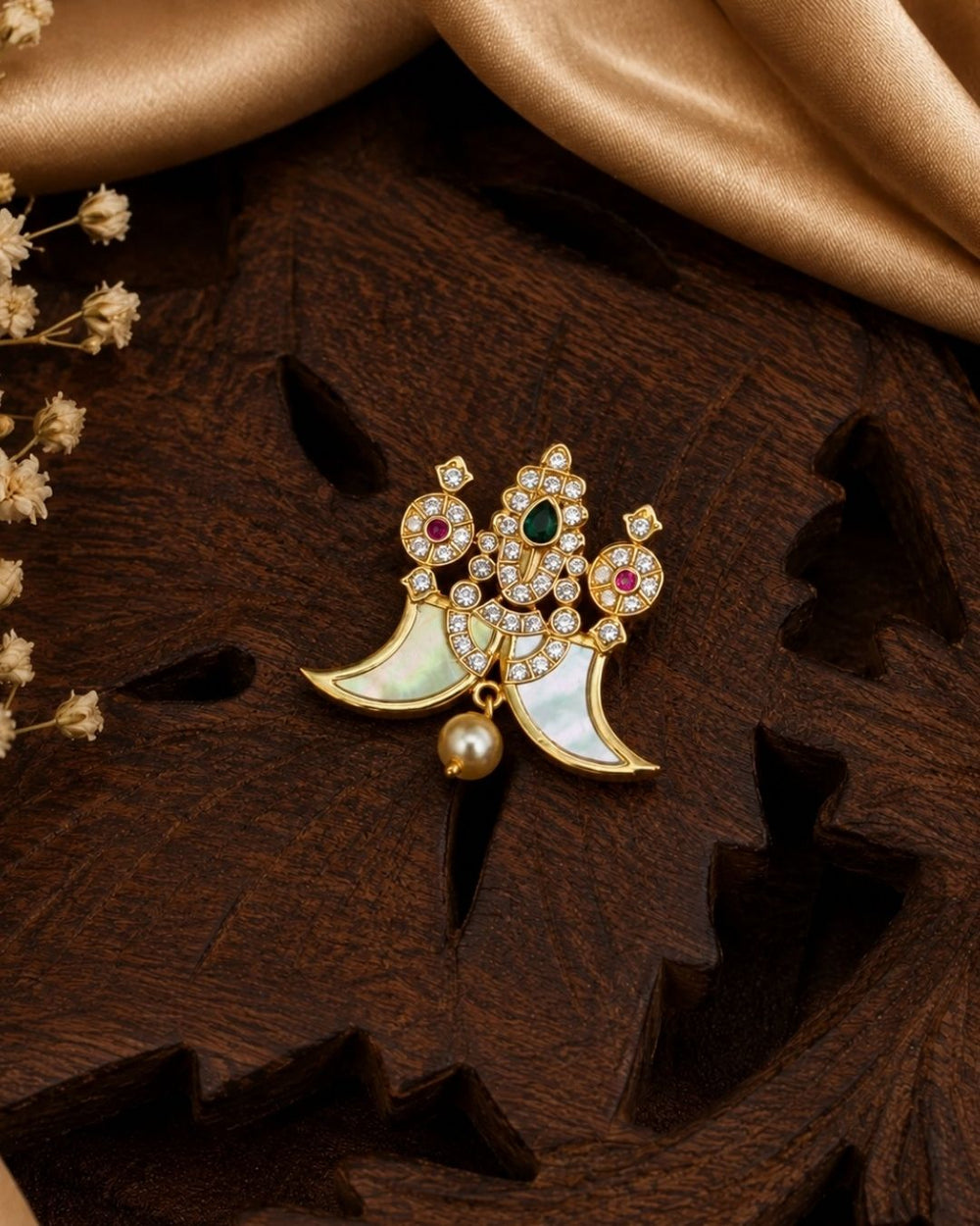 Shop this elegant gold plated peacock pendant featuring a green stone centerpiece, sparkling stones, mother-of-pearl accents, and a pearl drop. Perfect for festive and traditional occasions.