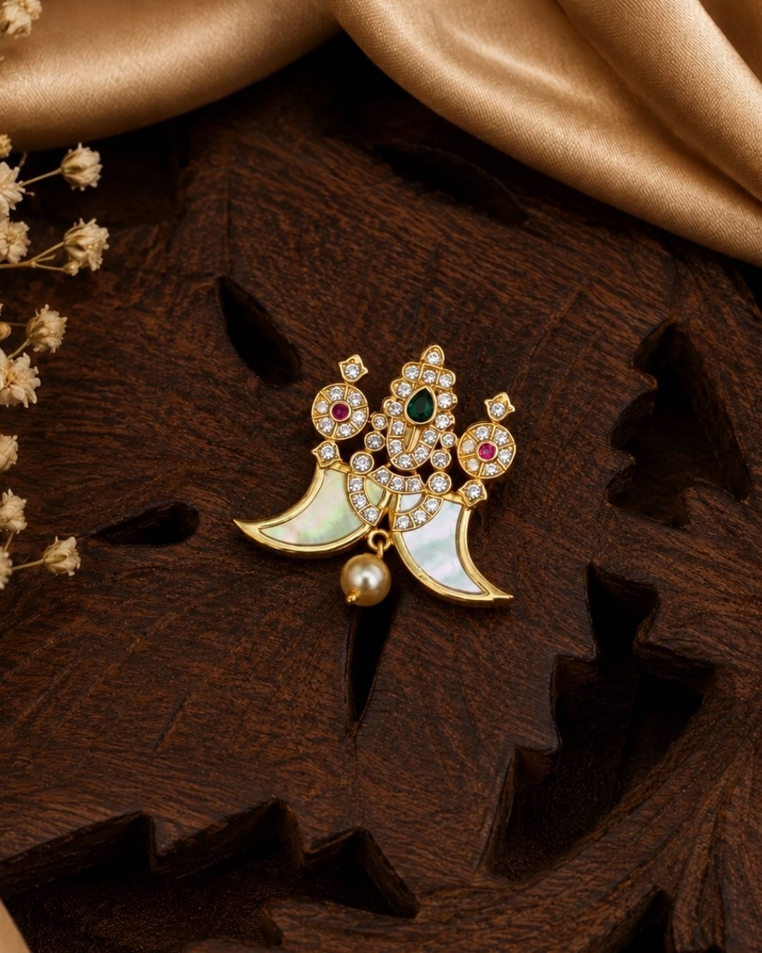 Shop this elegant gold plated peacock pendant featuring a green stone centerpiece, sparkling stones, mother-of-pearl accents, and a pearl drop. Perfect for festive and traditional occasions.