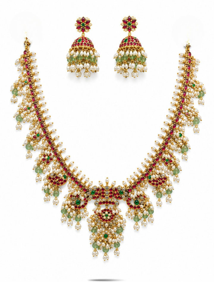 Gold necklace Set with a detailed pendant and earrings  on a white background with green and red stones come with jadau kundan in necklace set with beads and in pendent shows clear design and in detailed shown in picture it will not fade color and water proof can used for festivals, bridals, and weeding's  