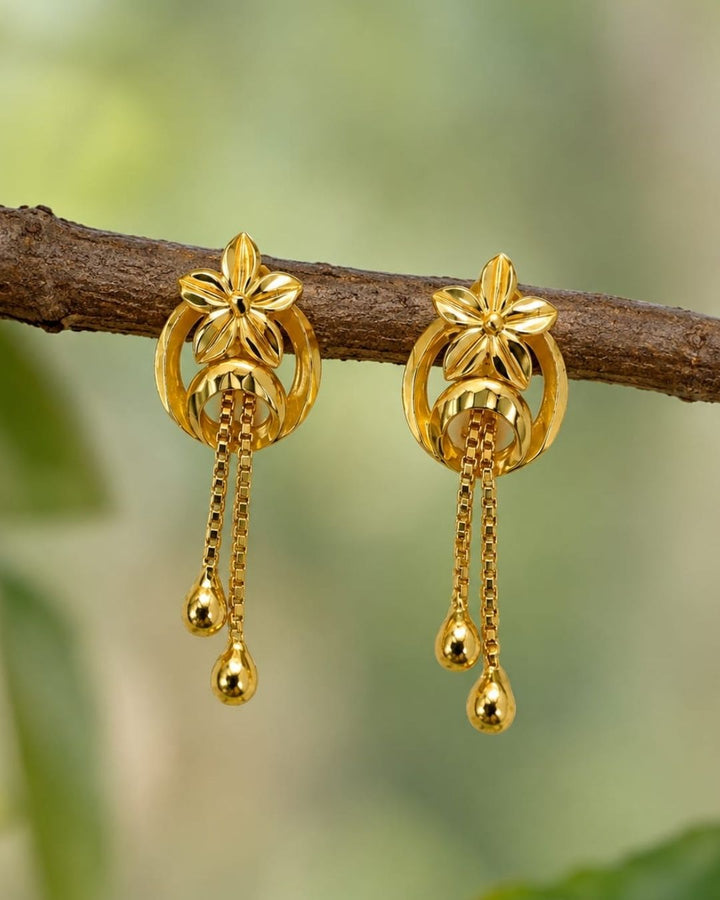 Stylish gold plated floral drop earrings featuring a detailed flower motif, elegant circular design, delicate hanging chains, and polished gold ball drops. Perfect for everyday wear, festive occasions, traditional outfits, parties, and special events.