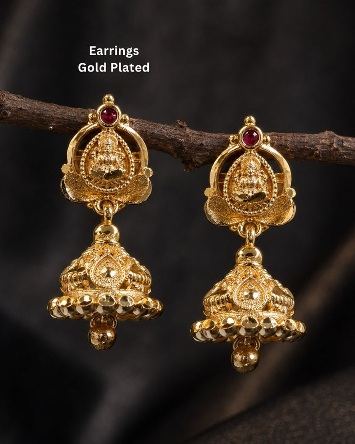 Beautiful traditional gold plated Lakshmi jhumka earrings featuring intricate temple-inspired craftsmanship, red stone detailing, ornate floral patterns, and hanging gold beads. Perfect for sarees, festive occasions, weddings, and traditional events.