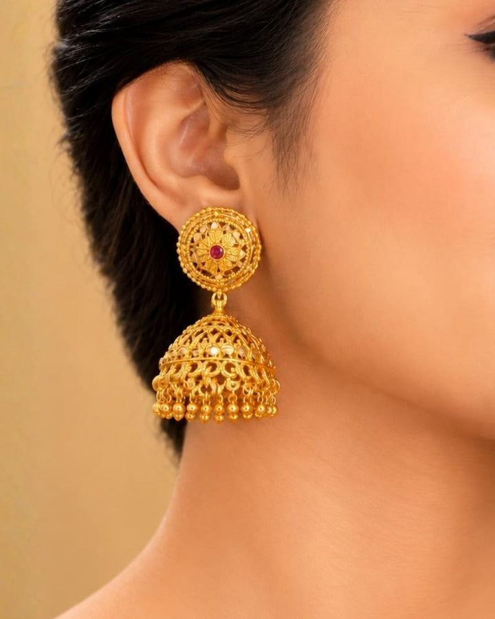 Beautiful traditional gold plated jhumka earrings featuring ornate floral stud designs, red stone accents, intricate filigree-style detailing, and elegant hanging gold beads. Perfect for sarees, festive occasions, weddings, and traditional events.