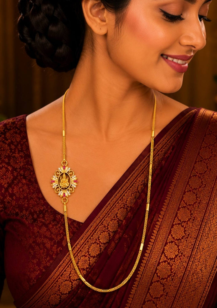 Woman wearing  a gold plated laxmi traditional gold plated thali chain featuring a beautifully crafted central Goddess Lakshmi mogappu side pendant embellished with sparkling white zircon stones and ruby pink gemstone accents. This high-quality classic woven chain design mimics a premium gold wedding chain, providing a rich and traditional appearance suitable for weddings, festivals, poojas, daily wear, family functions, traditional sarees, and ethnic outfits with skin-friendly quality, anti-fade long-lasti