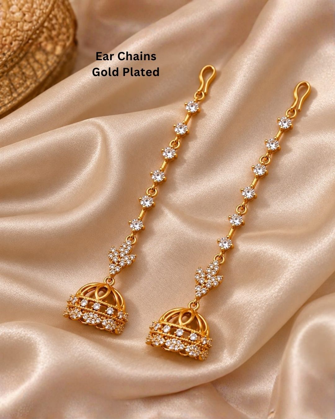 Traditional gold plated ear chain with matching jhumka earrings displayed against a carved wooden background with colourful floral accents.