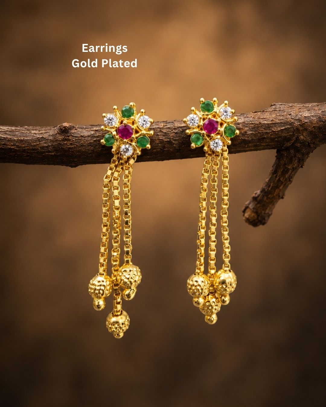 Stylish gold plated long drop earrings featuring vibrant ruby and green stones, sparkling white accents, intricate gold detailing, multiple hanging chains, and decorative gold ball drops. Perfect for festive occasions, traditional outfits, weddings, parties, and special events.