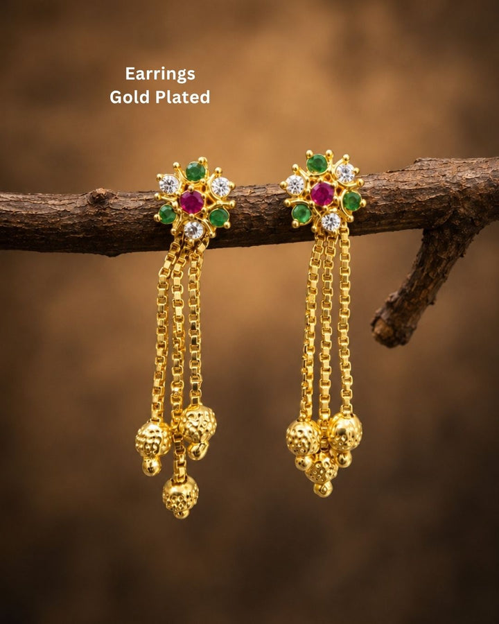 Stylish gold plated long drop earrings featuring vibrant ruby and green stones, sparkling white accents, intricate gold detailing, multiple hanging chains, and decorative gold ball drops. Perfect for festive occasions, traditional outfits, weddings, parties, and special events.