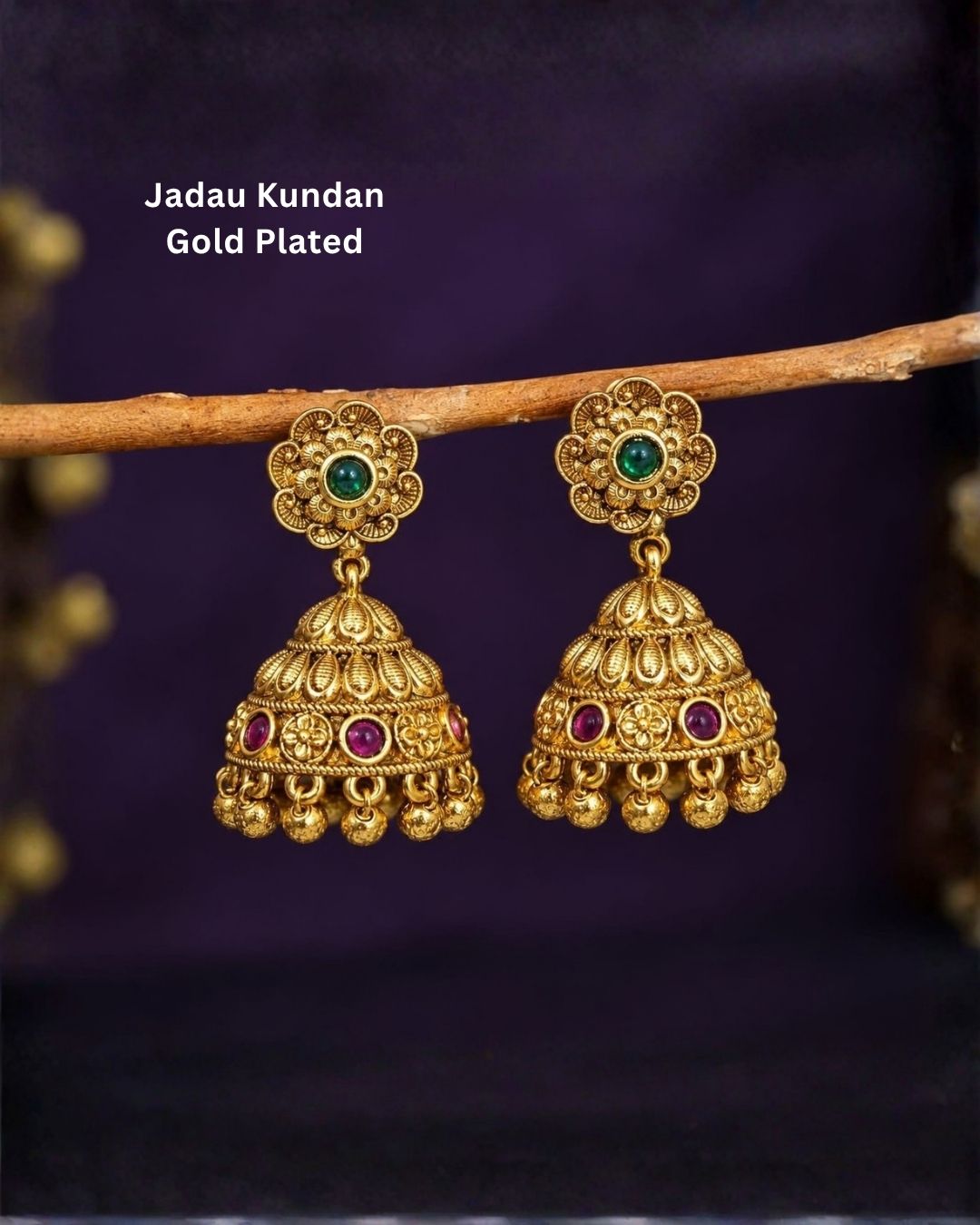 Traditional gold plated jhumka earrings featuring intricate floral motifs, green center stones, ruby-colored embellishments, detailed dome-shaped drops, and hanging gold beads, perfect for festive and traditional occasions.