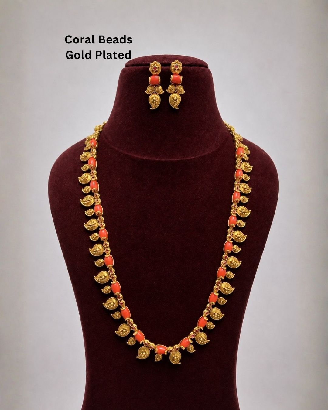 Traditional gold plated long necklace featuring a detailed chain of red beads and intricate gold leaf motifs with dangling coin embellishments. Perfect for weddings, festive occasions, traditional wear, bridal styling, parties, and special occasions.