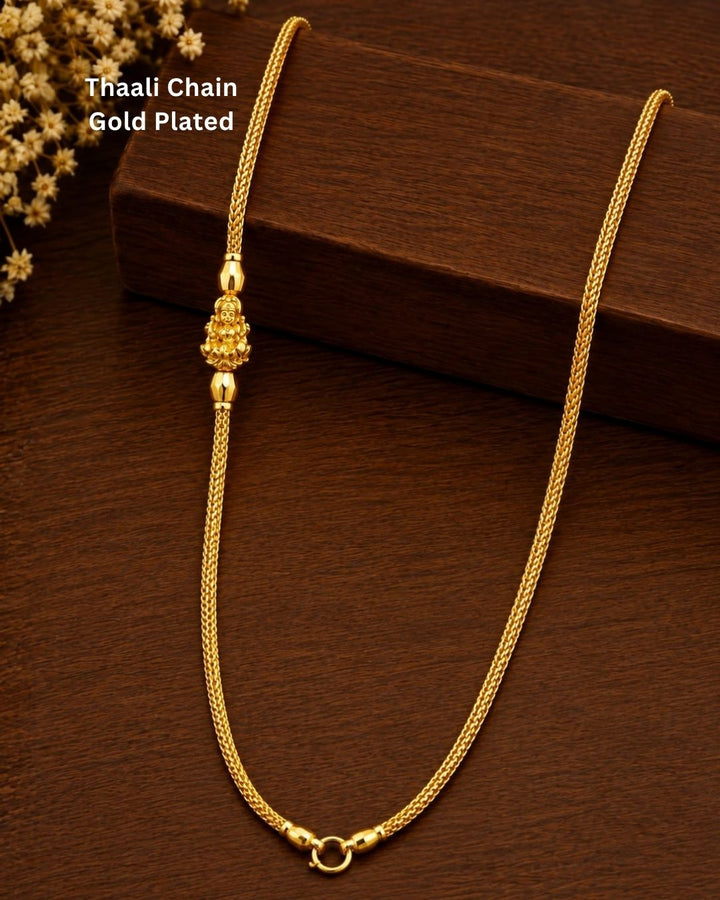 Gold plated thaali chain displayed on a dark wooden surface, highlighting its delicate links and traditional Lakshmi Devi design.