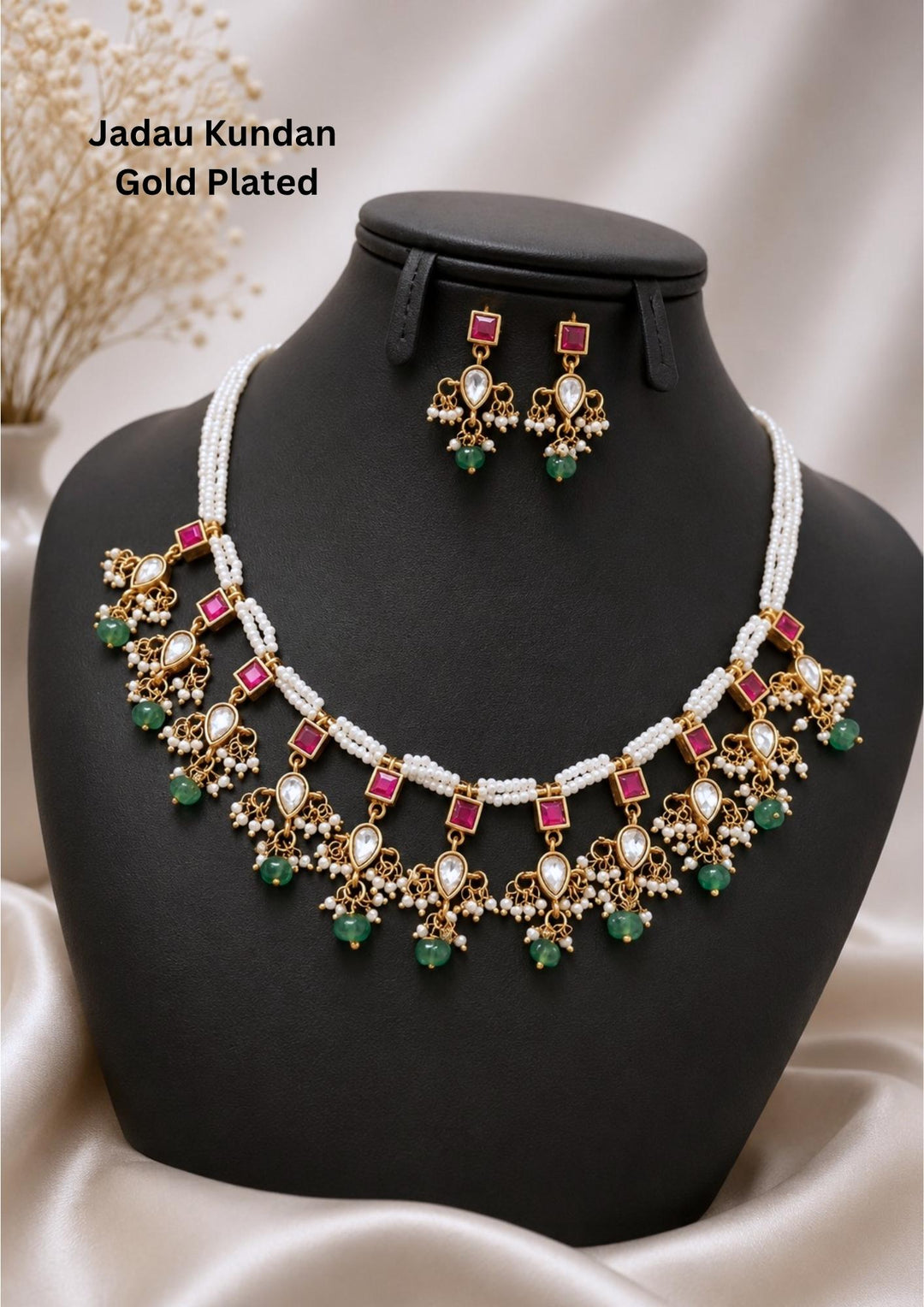 gold plated Jadau Kundan jewelry set designed with a multi-strand white seed pearl choker necklace. The necklace is with gold-toned drops set with square pink stones, teardrop white Polki Kundan elements, and tiny pearl clusters, finished with dangling mint green tumbles. Includes a matching pair of elegant hanging earrings. Ideal for weddings, festive occasions, and parties with skin-friendly premium quality
