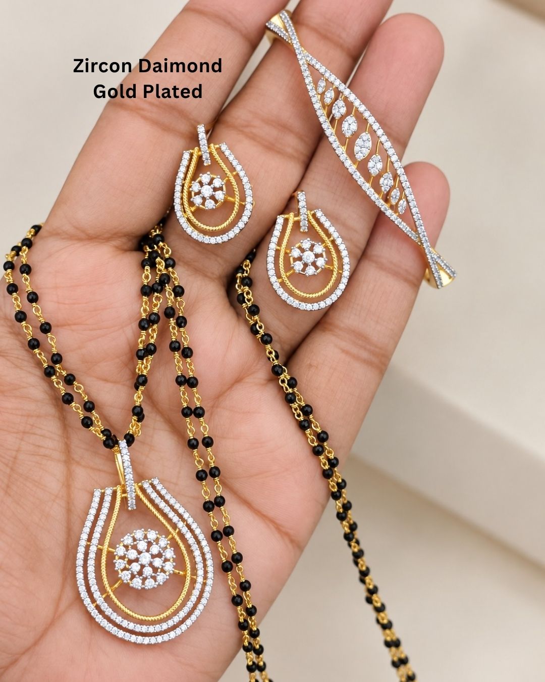 Elegant gold plated mangalsutra for women featuring multiple black bead strands, intricate zircon detailing, and matching teardrop-shaped earrings with a polished finish.