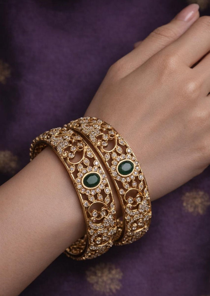 Close-up of a south indian woman wearing Gold Plated Emerald Bangles with green stone design and sparkling zircon detailing that gives a rich bridal and festive jewelry look. The bangles show detailed traditional design with lightweight comfort, sweat proof finish, anti-fade colour, smooth fitting, and are suitable for weddings, receptions, festivals, and family celebrations.